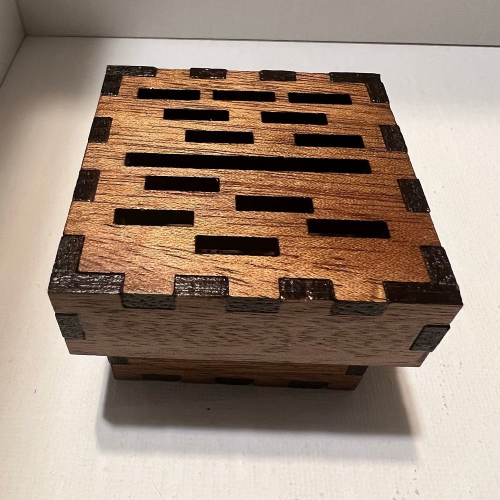 A medium reddish brown wood box with randomly placed rectangular slots on top of the lid