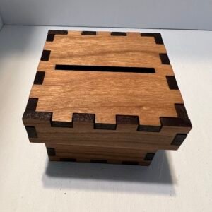 Front view of light brown wood box with a narrow horizontal slot on top side of lid.