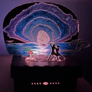 Couple dances on beach in front of panorama sunrise that is emitting blue and purple hues.